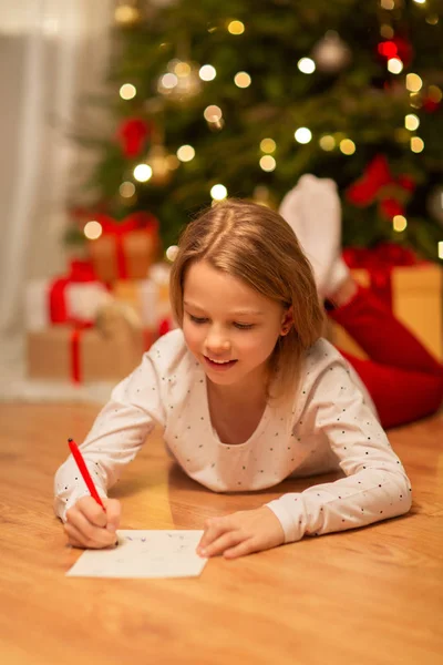 Usmívající se dívka psaní seznamu přání Vánoce doma — Stock fotografie