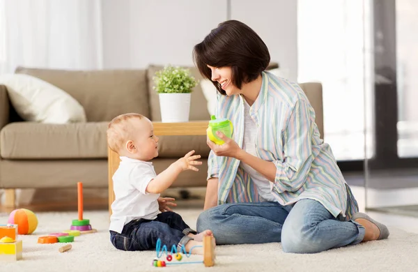 Glückliche Mutter schenkt ihrem kleinen Sohn zu Hause eine Tasse Schluck — Stockfoto