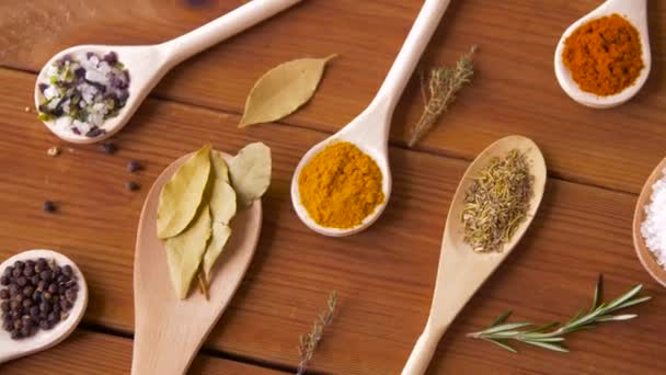 Spoons with different spices on wooden table — Stock Video