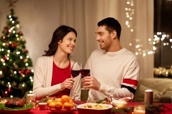 Счастливая пара пьет красное вино на рождественском ужине — стоковое фото