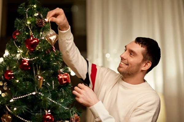 Счастливый человек украшает елку дома — стоковое фото