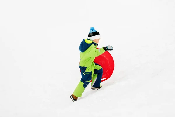 Niño feliz con platillo de nieve trineo en invierno —  Fotos de Stock