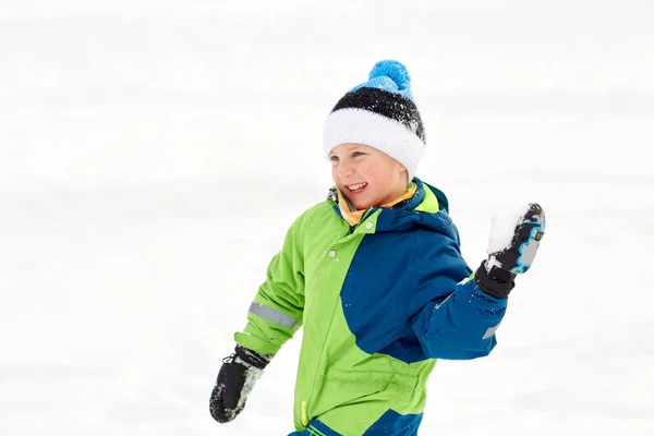 Menino feliz jogando e jogando bola de neve no inverno — Fotografia de Stock