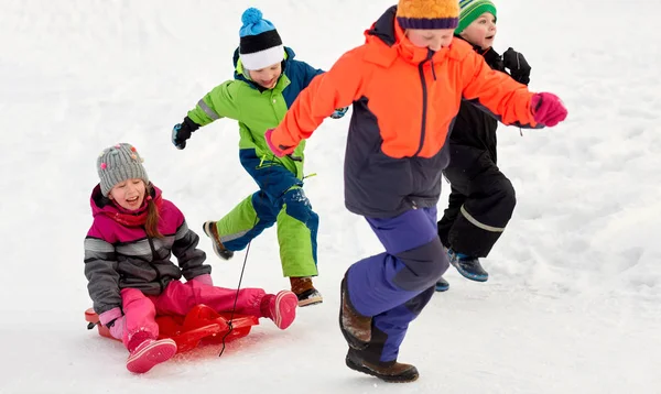 休闲和季节概念 小组的快乐的小朋友在冬季的衣服与雪橇有乐趣户外 — 图库照片