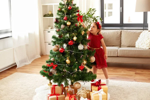 Kleines Mädchen schmückt Weihnachtsbaum zu Hause — Stockfoto