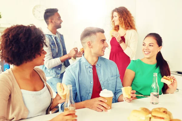 Happy friends or team eating at office — Stock Photo, Image