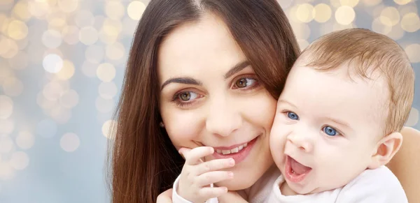 Mãe com bebê sobre luzes festivas fundo — Fotografia de Stock