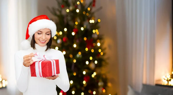 Smiling woman in santa hat with christmas gift — Stock Photo, Image