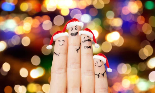 Gros plan de quatre doigts dans des chapeaux de Père Noël sur les lumières — Photo
