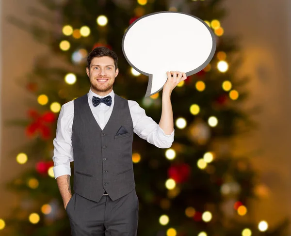 Homem segurando bolha de texto em branco sobre árvore de natal — Fotografia de Stock