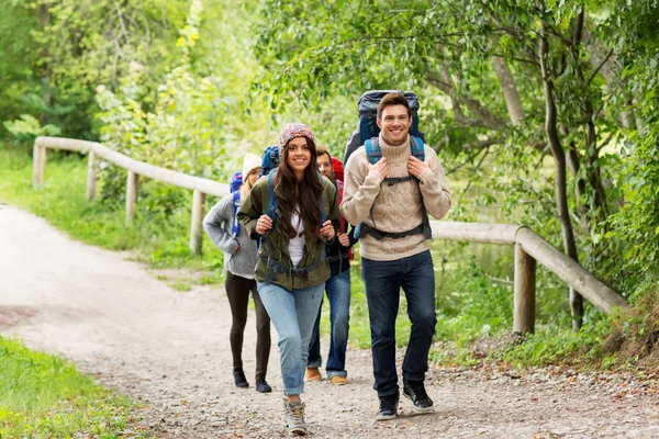 Happy friends or travelers hiking with backpacks — Stock Photo, Image