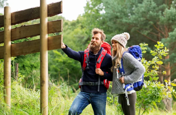 Pareja de viajeros con mochilas en la señal — Foto de Stock