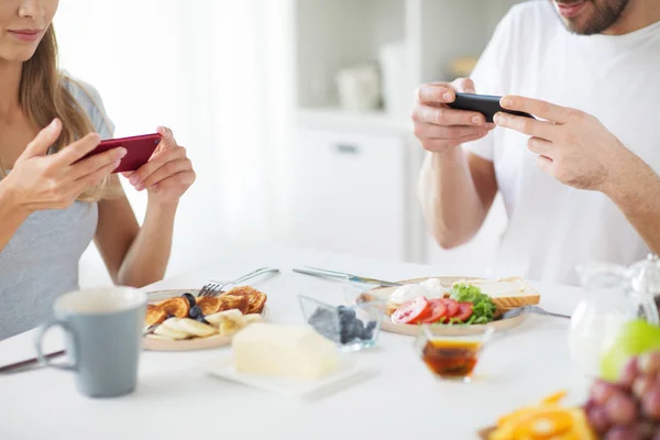 Gros plan du couple avec smartphones au petit déjeuner — Photo