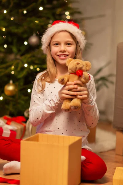 Smiling girl in santa hat with christmas gift — Stock Photo, Image