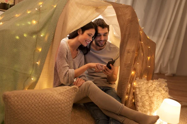 Casal feliz com smartphone na tenda crianças em casa — Fotografia de Stock