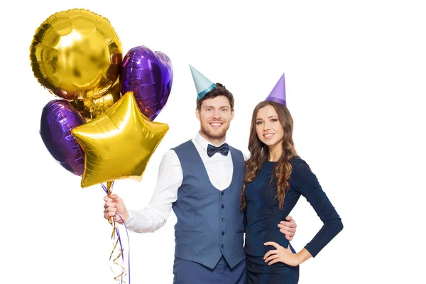 Feliz pareja con gorras de fiesta y globos — Foto de Stock