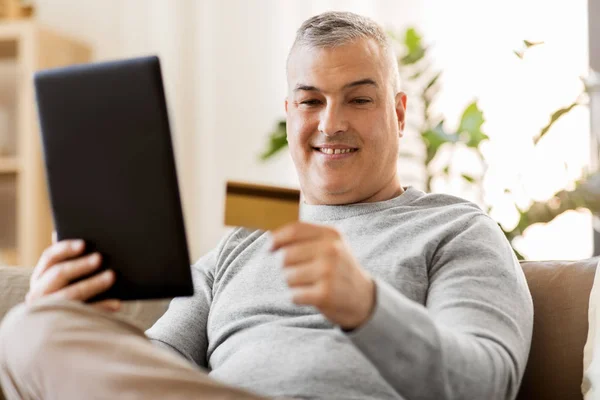 Mann mit Tablet-PC und Kreditkarte zu Hause auf Sofa — Stockfoto