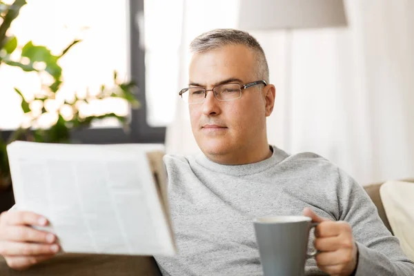 Pria membaca koran dan minum kopi di rumah — Stok Foto