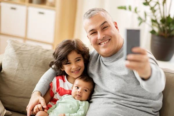 Pai feliz com filhos tomando selfie em casa — Fotografia de Stock