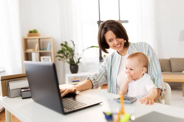 working mother with baby boy and laptop at home