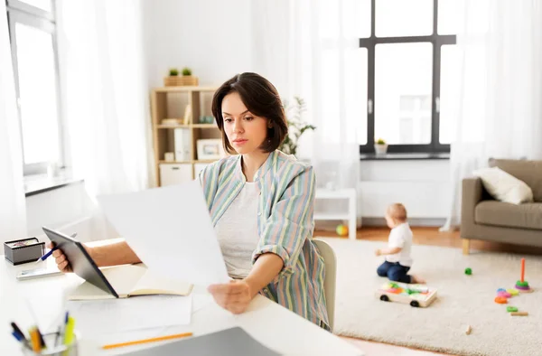 Madre trabajadora con tableta PC y papeles en casa —  Fotos de Stock