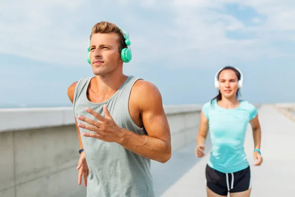 Pareja con auriculares corriendo al aire libre — Foto de Stock