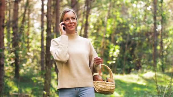 Frau mit Pilzen telefoniert mit Handy im Wald — Stockvideo