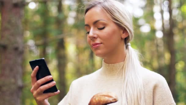 Woman with mushroom and smartphone in forest — Stock Video