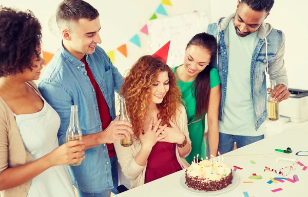 happy coworkers with cake at office birthday party