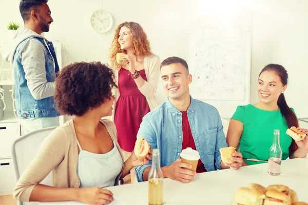 Happy friends or team eating at office — Stock Photo, Image