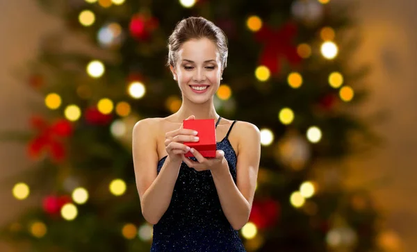 Donna con scatola regalo rossa sopra le luci dell'albero di Natale — Foto Stock