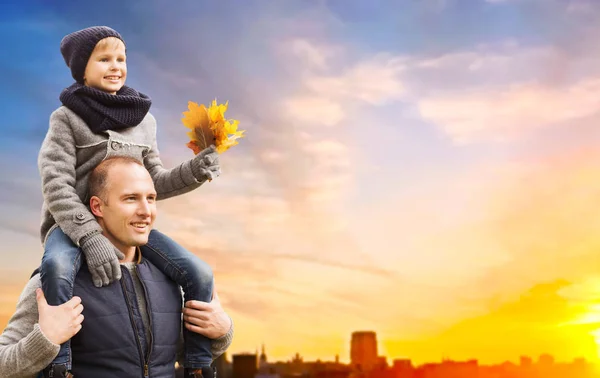 Padre llevando hijo con hojas de otoño en la ciudad — Foto de Stock