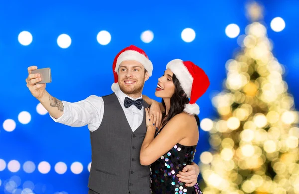 Casal em santa chapéus fazendo selfie no Natal — Fotografia de Stock