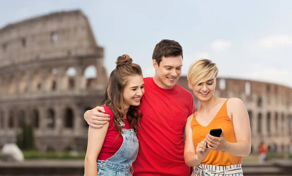 Друзья со смартфоном на фоне Колизея — стоковое фото
