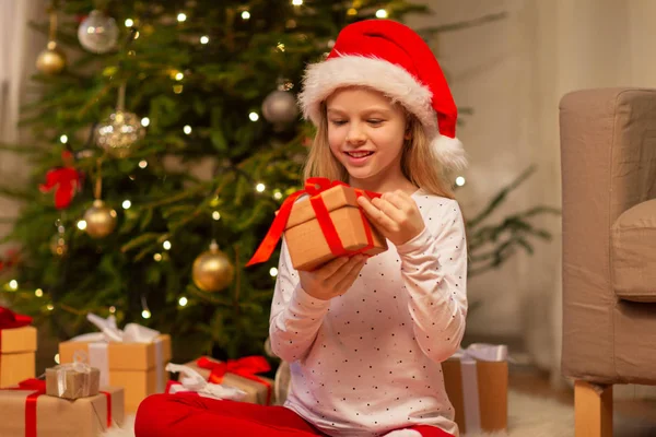 Chica sonriente en sombrero de santa con regalo de Navidad —  Fotos de Stock