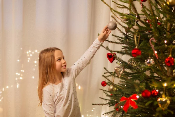 Glad flicka i röd klänning dekorera julgran — Stockfoto
