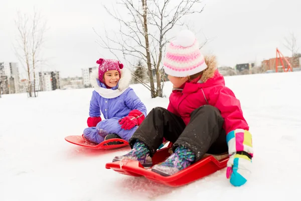 Meninas felizes em trenós ao ar livre no inverno — Fotografia de Stock
