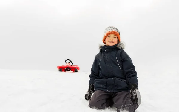 Heureux garçon et traîneau sur la colline de neige en hiver — Photo
