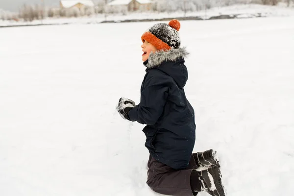 Glücklicher kleiner Junge, der im Winter mit Schnee spielt — Stockfoto