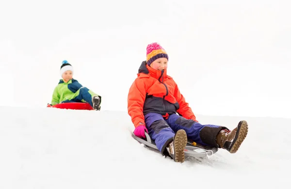 Happy kids sliding on sleds down hill in winter — Stock Photo, Image