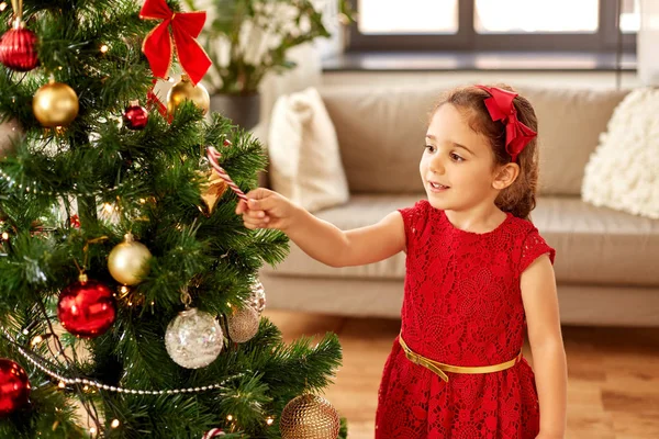 Kleines Mädchen schmückt Weihnachtsbaum zu Hause — Stockfoto