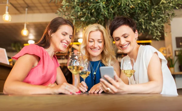 Kvinnor med smartphone på vin bar eller restaurang — Stockfoto