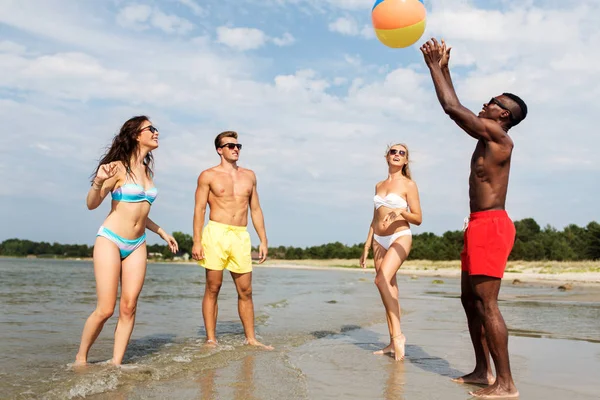 Vrienden met strandbal spelen in de zomer — Stockfoto