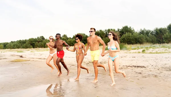 Šťastní přátelé běží na letní pláži — Stock fotografie