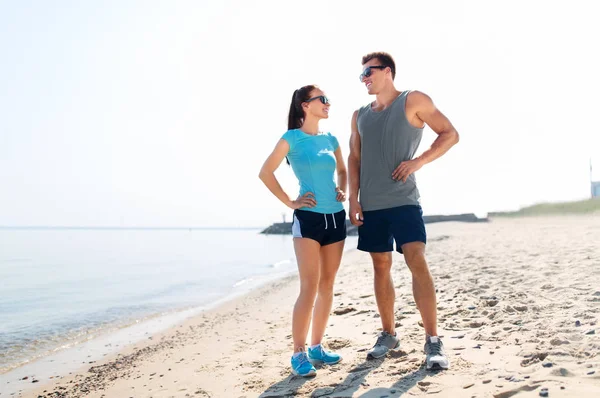 快乐的情侣在运动衣和阴影在海滩上 — 图库照片