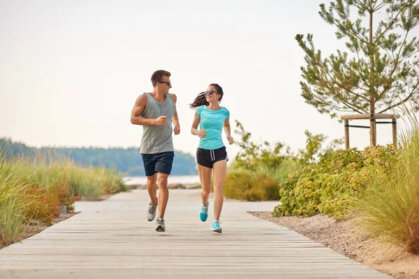 Paar in sporten kleren loopt langs strand pad — Stockfoto