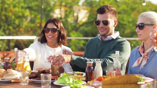 Щасливі друзі їдять і п'ють на вечірці на даху — стокове відео