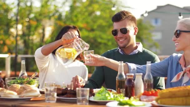 Счастливые друзья едят и пьют на вечеринке на крыше — стоковое видео