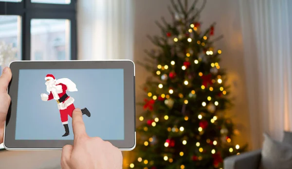 Hände mit Weihnachtsmann-Bild auf Tablet-PC-Bildschirm — Stockfoto