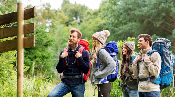 Hiking friends with backpacks at signpost — Stock Photo, Image